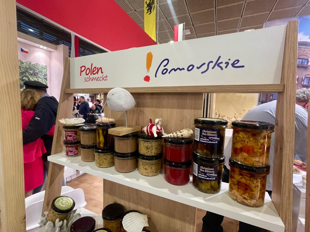 Półka ze słoikami z przetworami z ryb. U góry na półce widnieje napis POLEN SCHMECKT i logo POMORSKIE